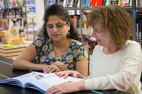 twee vrouwen met boek in de bibliotheek