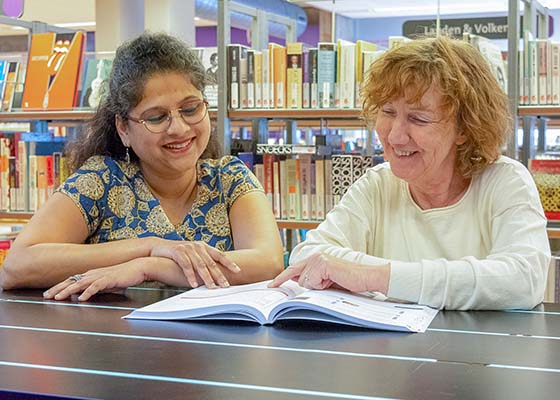 twee vrouwen bestuderen boek in de bibliotheek