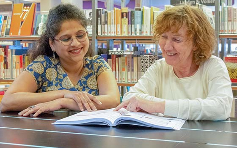twee vrouwen bestuderen boek in de bibliotheek